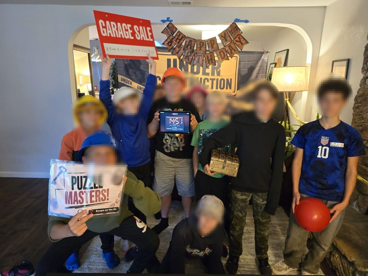 A birthday group holding up their Puzzle Masters certificate and the game timer after escaping a room we set up in their living room